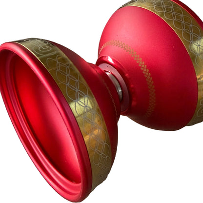 Starlight plus red and gold yo-yo. The yo-yo features a red body with a matte gold decorative band containing an interlocking geometric pattern.
