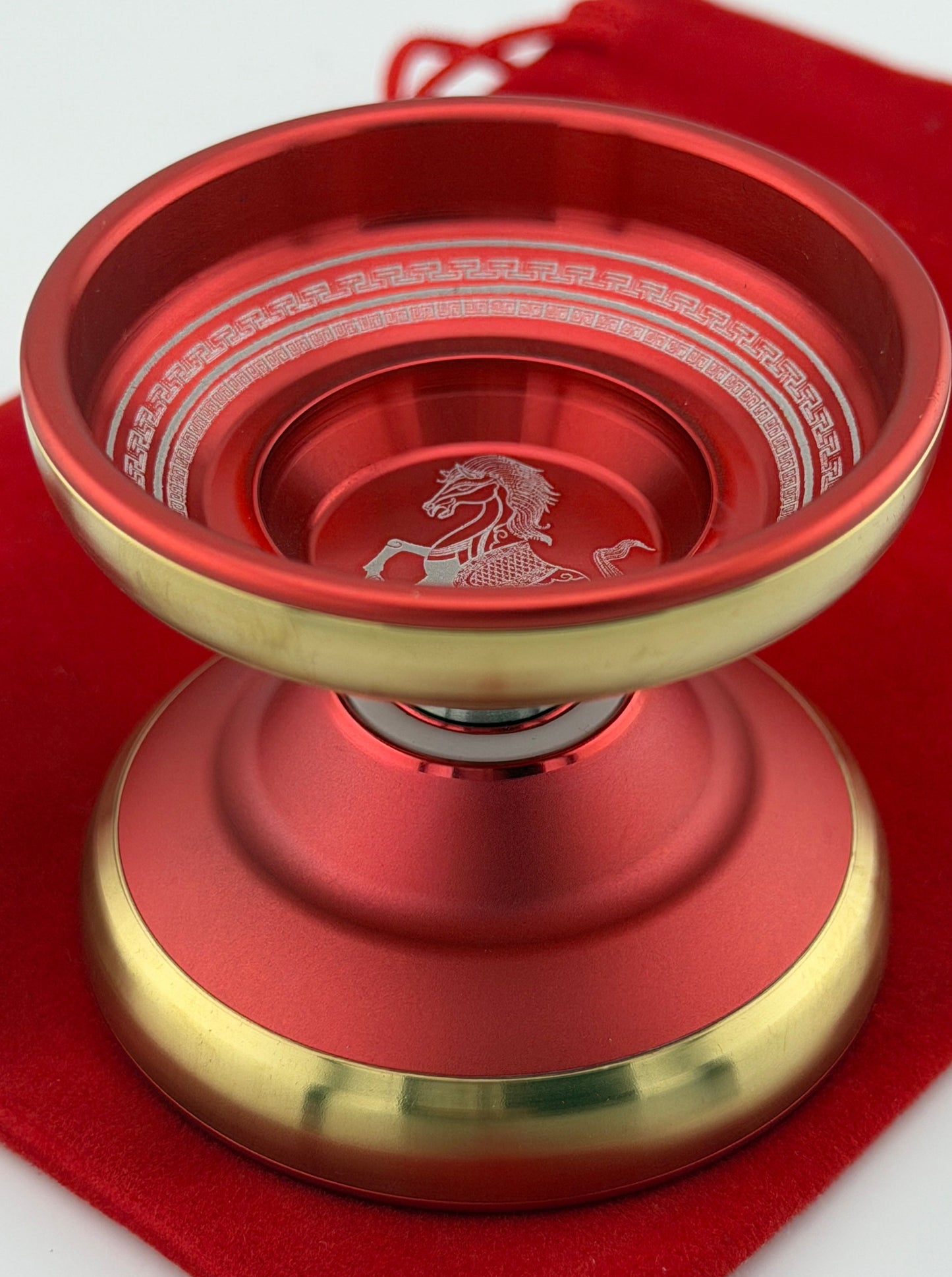 Red and gold yoyo with a horse emblem on a red cloth background